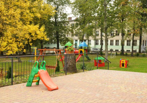 Widok z tarasu przedszkolnego na przedszkolne sprzęty ogrodowe dla dzieci
