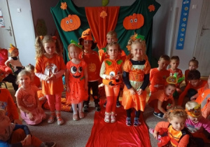 Dzieci w przebraniach z okazji Pomarańczowego dnia na tle dekoracji.