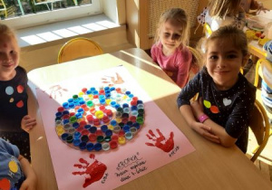 Innna grupa dziewczynek z grupy Tygrysów wykonała kreatywną pracę plastyczną. Przyklejły kolorowe plastikowe korki od butelek typu PET w szablonie koła na dużym różowym kartonie. W ten sposób stworzyły wielką kropkę z korków.