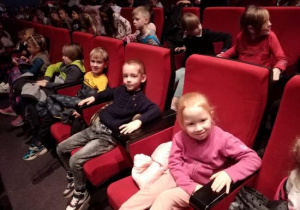 Dzieci z grupy Tygrysów siedzą w fotelach teatralnych w oczekiwaniu na przedstawienie.