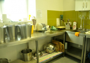 Dobrze wyposażona kuchnia w sprzęty pomocne w przygotowywaniu i serwowaniu posiłków dla przedszkolaków.