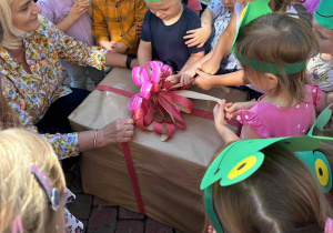 Dzieci w czasie odpakowania prezentu z okazji Dnia Przedszkolaka.