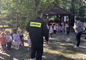 Strażak rozawiający z przedszkolakami na temat bezpieczeństwa przeciwpożarowego w przedszkolu.