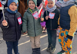 Dzieci trzymają chorągiewki z barwami narodowymi.