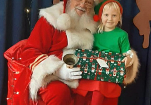 Dziewczynka z grupy Jeżyków pozuje do zdjęcia z Mikołajem.